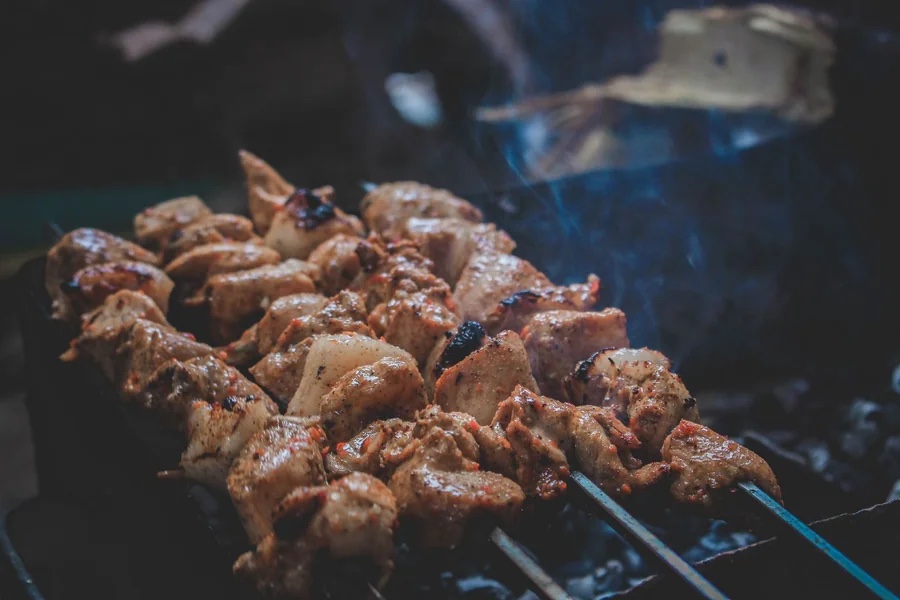 Meat skewers cooking over a charcoal grill